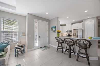 Kitchen with a breakfast bar, white cabinetry, stainless steel appliances, light tile patterned floors, and recessed lighting