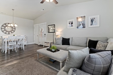 Living area featuring vaulted ceiling, chandelier, ceiling fan