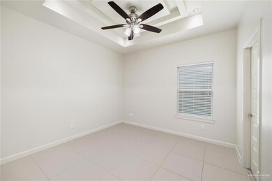 Empty room featuring baseboards, a tray ceiling, and a ceiling fan