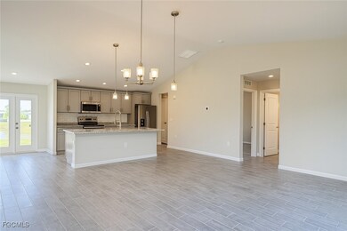 Kitchen featuring an island with sink, decorative light fixtures, tasteful backsplash, a chandelier, and open floor plan