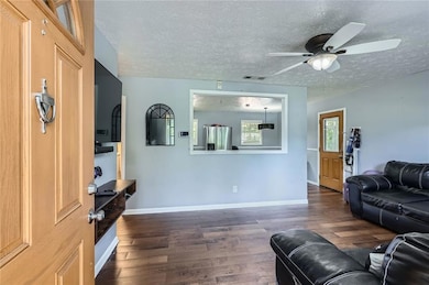 Living room featuring wood finished floors, a ceiling fan, and a textured ceiling