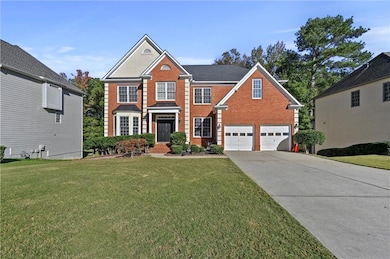View of front of home featuring driveway, brick siding, a garage, and a front lawn