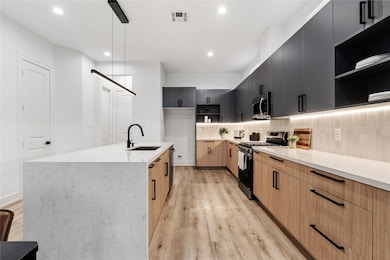 A chef’s dream with bold contrast
and meticulous detail — the
kitchen pairs sleek grey
cabinetry with soft oak-colored
flooring and a waterfall quartz
island that anchors the space.