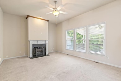 living room with a fireplace with flush hearth, carpet, and a ceiling fan