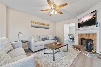 Living room featuring a brick fireplace, ceiling f