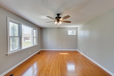 Spacious Living Room with views to Front Yard!  Arched Doorways leading to Eat In Kitchen & one leads to 2 of the 3 Bedrooms. Beautifully renewed hardwood floors, Ceiling Fan & Freshly Painted. 