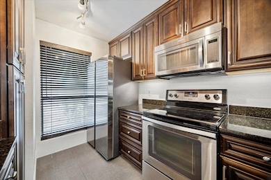 Kitchen with dark stone counters, stainless steel