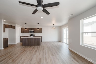 Kitchen with light countertops, pendant lighting, light wood finished floors, recessed lighting, and open floor plan