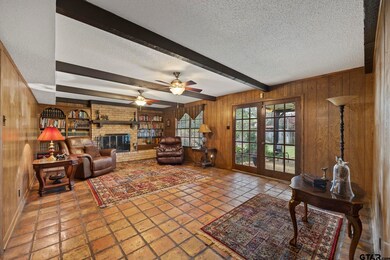 Spacious family room with wood-burning fireplace, french doors to back patio & ceiling beams.