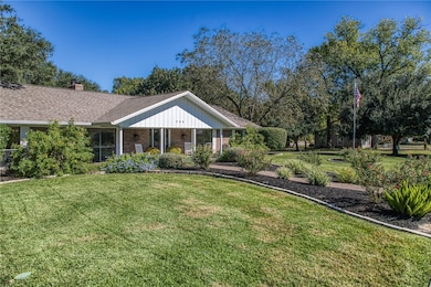 View of front of house featuring a porch, a front yard, brick siding, a chimney, and a shingled roof