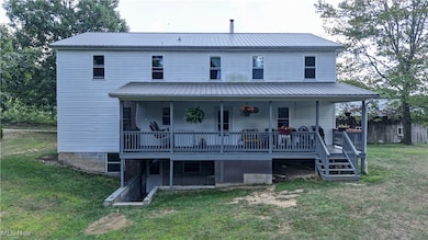 Back of house with covered porch, a yard, a metal roof, and stairs