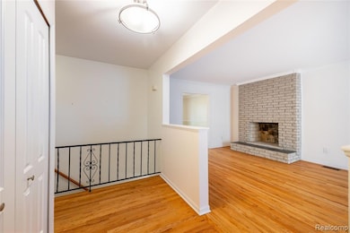 Corridor featuring an upstairs landing, wood finished floors, and crown molding