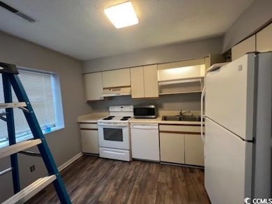 Kitchen featuring sink, white appliances, dark woo