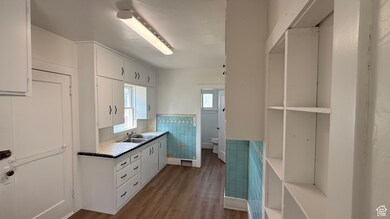 Kitchen featuring tile counters, white cabinets, tile walls, wainscoting, and dark wood finished floors