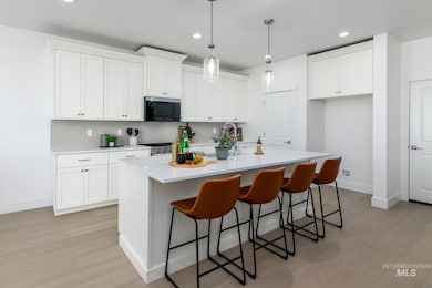 Kitchen with a kitchen bar, tasteful backsplash, stainless steel appliances, a kitchen island with sink, and white cabinetry