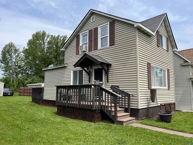 View of front of property with a front yard, a shingled roof, a deck, and cooling unit