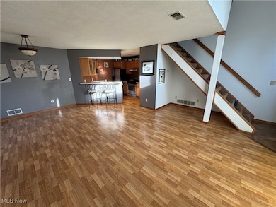 Unfurnished living room with a textured ceiling, light wood-style floors, and stairway