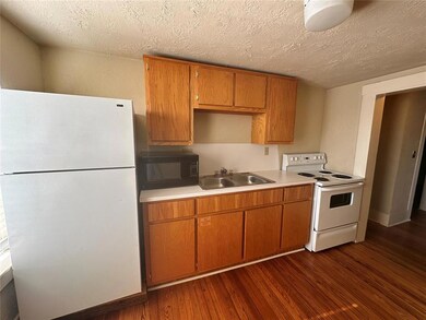 Kitchen featuring white appliances, a sink, dark wood-style floors, light countertops, and a textured ceiling