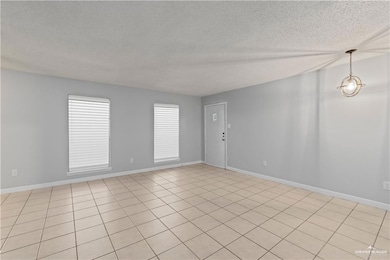 Empty room with a textured ceiling and light tile patterned floors