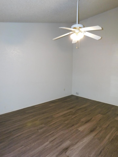 Spare room featuring ceiling fan and dark wood fi