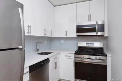 Kitchen featuring stainless steel appliances, tasteful backsplash, white cabinets, and light stone counters