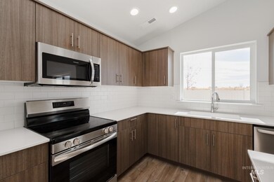 Kitchen with appliances with stainless steel finishes, lofted ceiling, dark wood finished floors, decorative backsplash, and recessed lighting