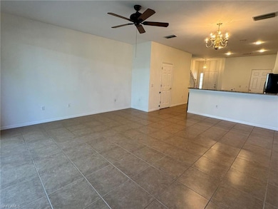 Unfurnished living room featuring a chandelier, a ceiling fan, and dark tile patterned floors