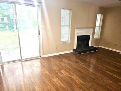 Unfurnished living room featuring wood finished floors and a fireplace with raised hearth