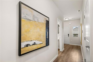 Hallway with wood finished floors, visible vents, 