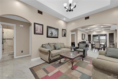 Tiled living room featuring a notable chandelier and a raised ceiling