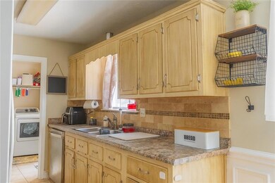 Kitchen featuring open shelves, washer / dryer, decorative backsplash, and light brown cabinetry