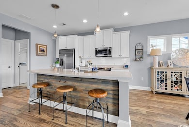 Open kitchen with large island, stainless appliances and tiled backsplash.