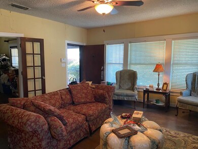 Living area featuring a ceiling fan, a textured ce