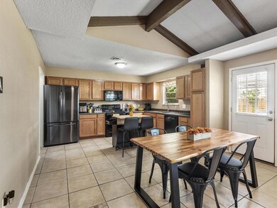 Tiled dining area with vaulted ceiling with beams,