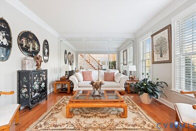 Living area with ornamental molding, wood finished floors, and stairs