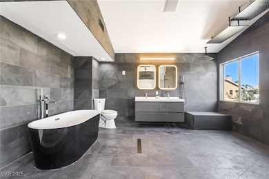Full bath featuring tile walls, double vanity, a freestanding bath, and a marble finish shower
