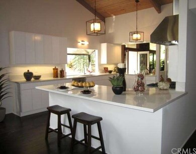 The gourmet kitchen features Viking appliances (refrigerator, microwave, dishwasher, freestanding range, hood), Caesarstone countertops, custom made cabinets, breakfast bar, and leads into the open dining room.