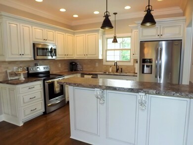 Gorgeous kitchen with hardwood floor, custom cabinetry and recessed lighting.