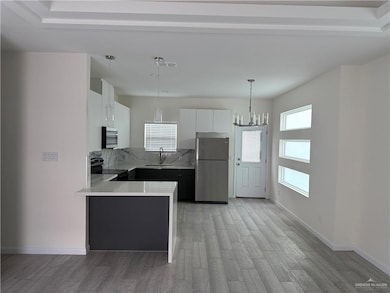Kitchen with stainless steel appliances, a sink, light wood-style floors, light countertops, and white cabinetry