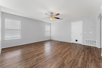 Empty room with a ceiling fan, arched walkways, a