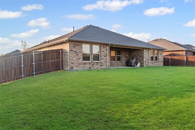 Rear view of property with a shingled roof, a patio area, brick siding, and a fenced backyard