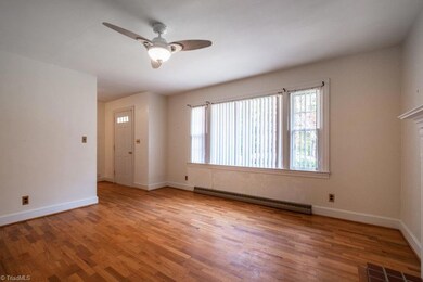Living room looking toward front door features ceiling fan, new windows and hardwood floors.