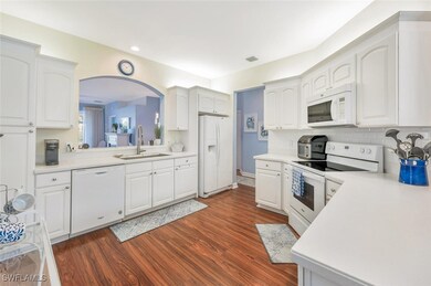 Kitchen with white cabinets, white appliances, dar