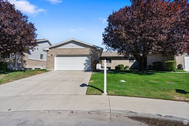 Single story home featuring brick siding, concrete driveway, an attached garage, and a front lawn