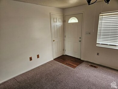 Entrance foyer with a textured ceiling and dark carpet
