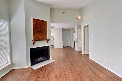 Unfurnished living room featuring wood finished floors, a fireplace with flush hearth, and a towering ceiling
