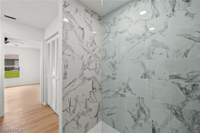 Bathroom featuring a tile shower, ceiling fan, and