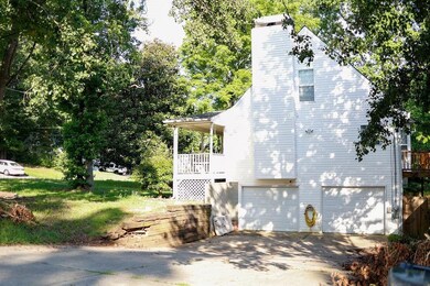 View of property exterior featuring driveway, an attached garage, and a chimney
