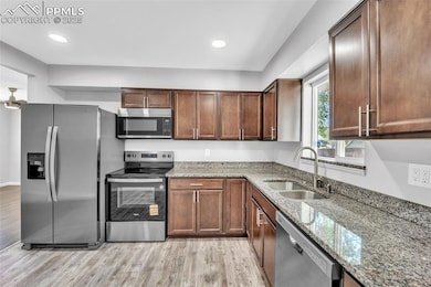 Kitchen with appliances with stainless steel finishes, light wood-style flooring, light stone countertops, and recessed lighting