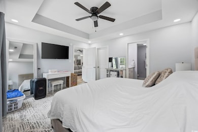 Bedroom featuring a ceiling fan, a tray ceiling, a